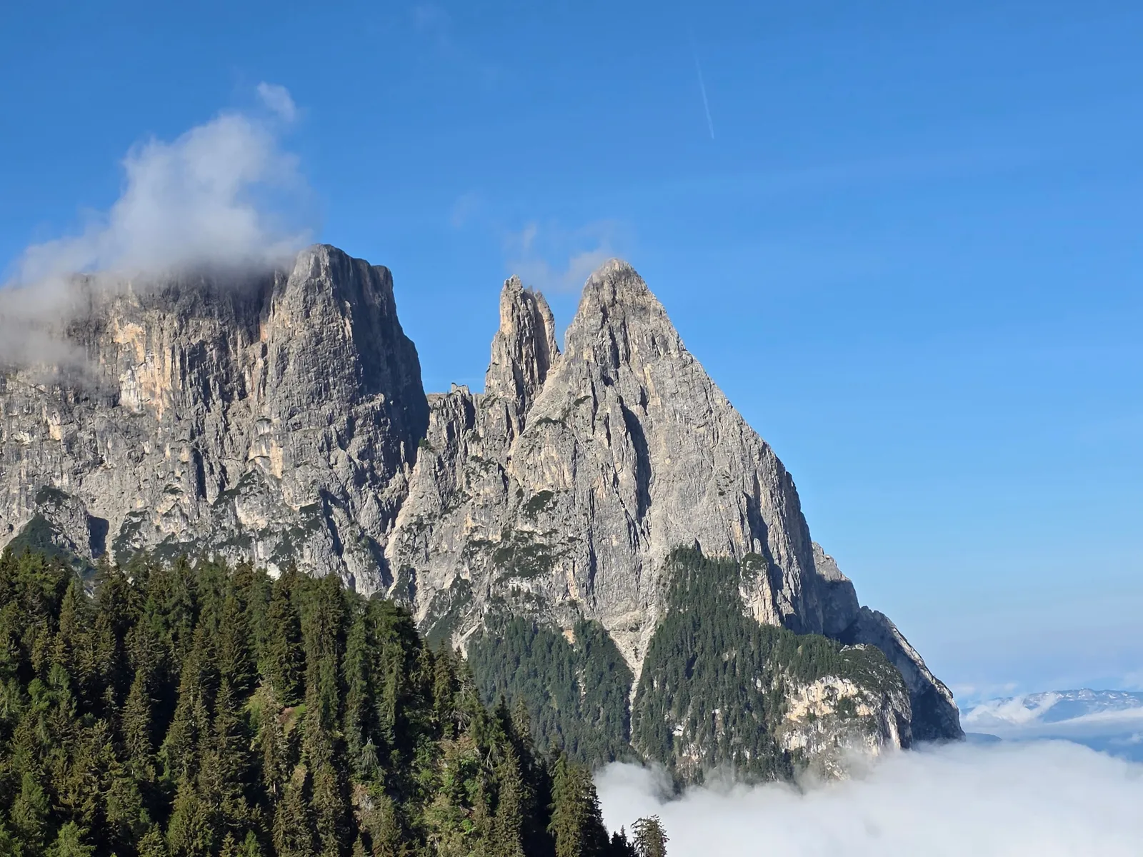 A hiking trail winding through green alpine meadows beneath dramatic limestone peaks in the Dolomites