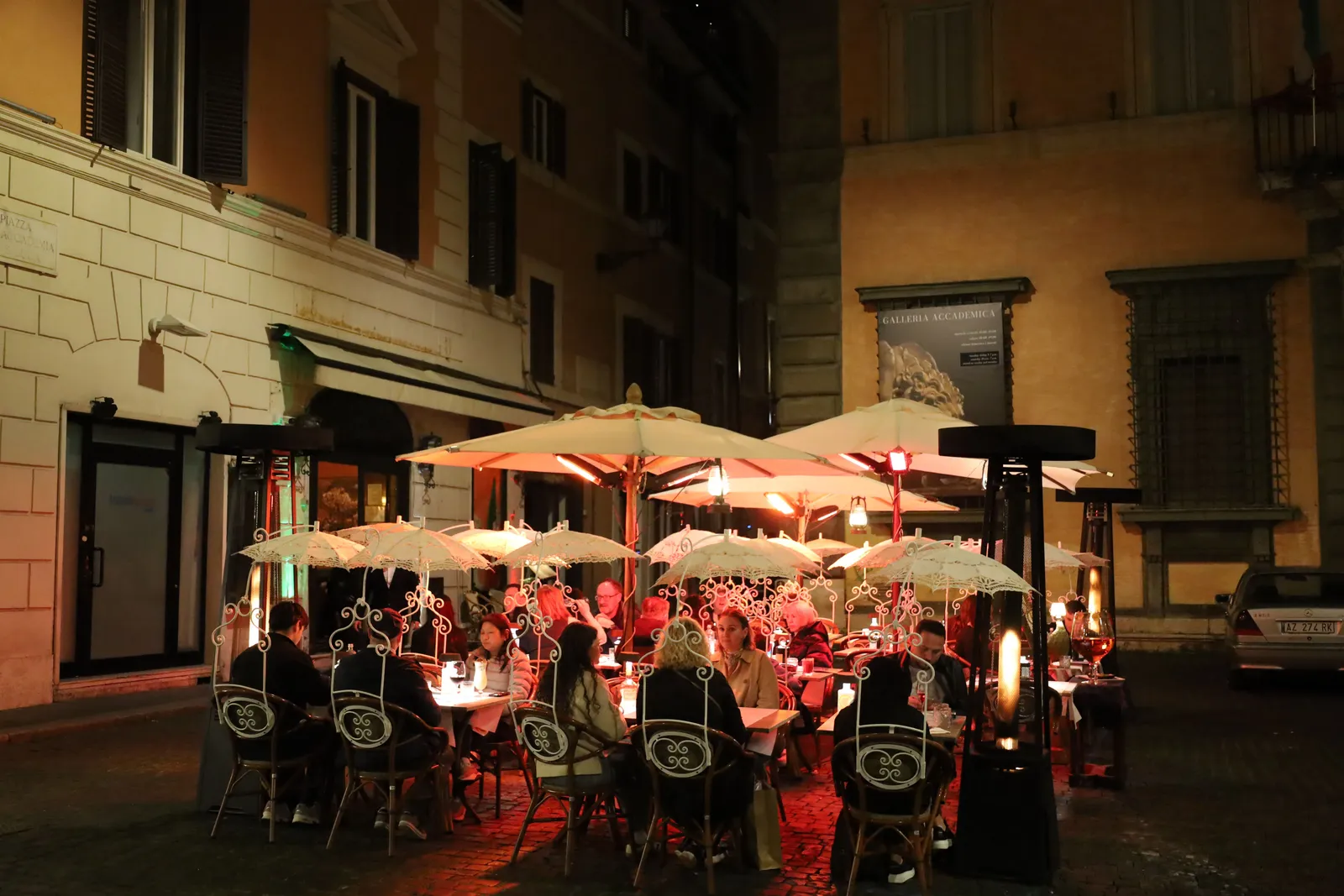 A narrow street of shuttered buildings and restaurant tables in Trastevere, Rome, Italy